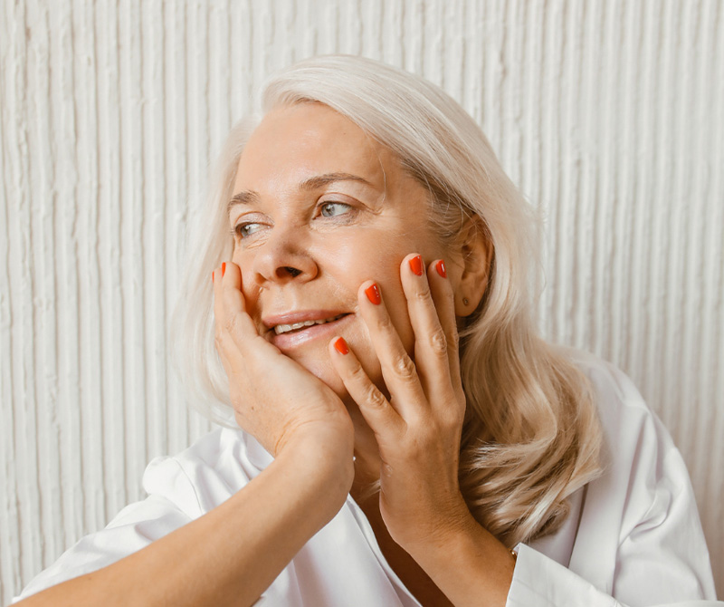 older lady resting her hands on her face, relaxed and happy
