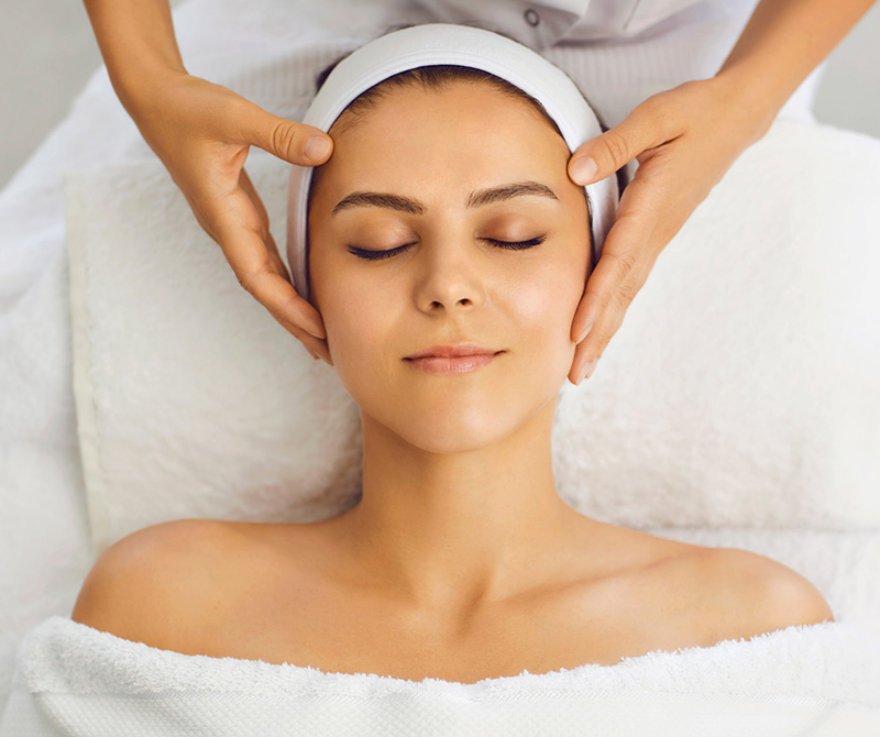 client having treatment, relaxed with practitioner's hands resting on face